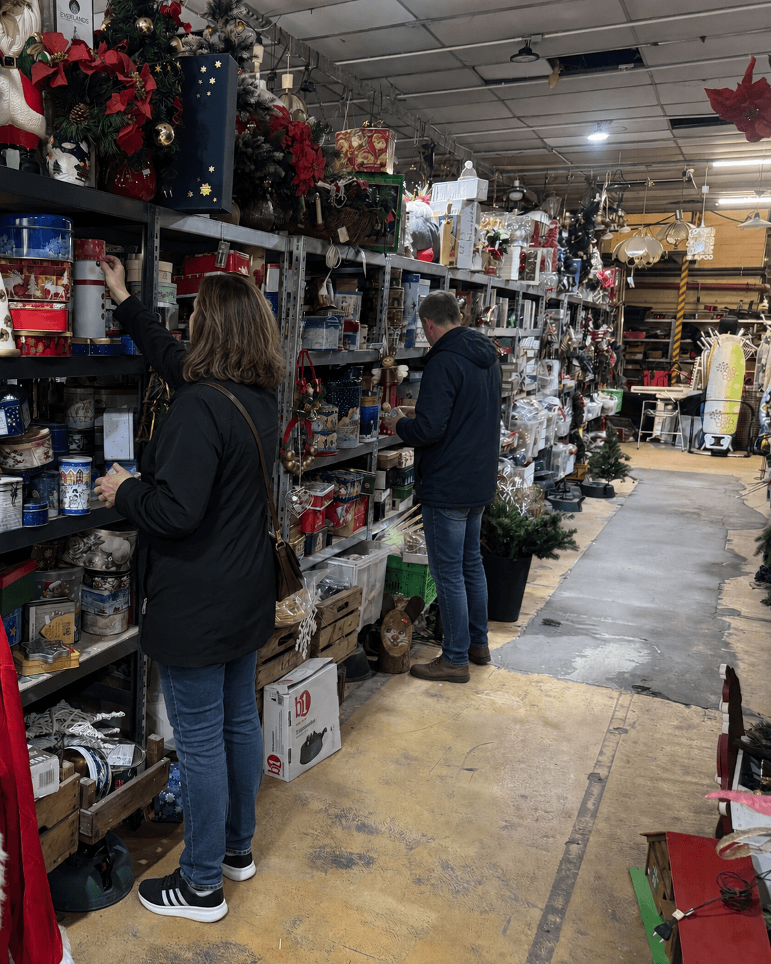 Eine Person geht einen Gang der Flohmarkthalle entlang und sieht sich die Regale an