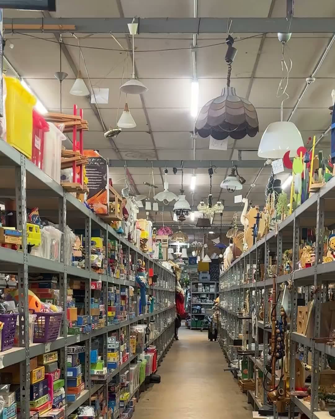 Fahrt durch einen Gang der Flohmarkthalle, links und rechts Regale voller Waren bis unter die Decke